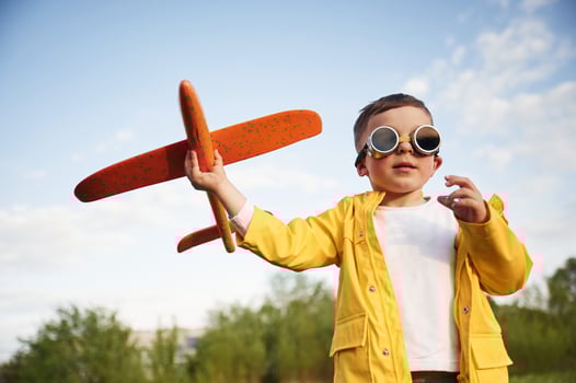 Red colored t,oy, plane. Little boy is playing on the summer field photo