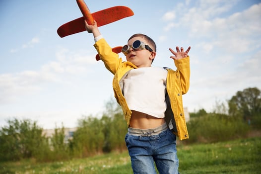 Aviato,r glasses are worn. Little boy is playing with toy plane on the summer field photo