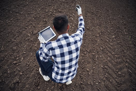 Cultivated agricultural field., Sitting, holding digital tablet. Handsome Indian man photo