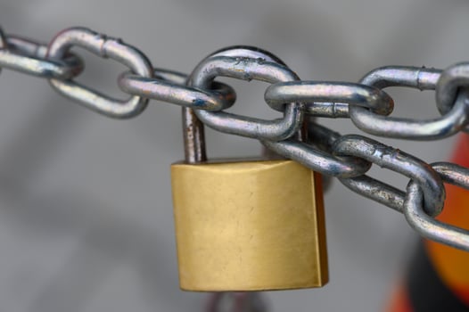 Metallic chain secured with a shiny golden padlock, symbolizing strength and safety in a bustling urban environment photo