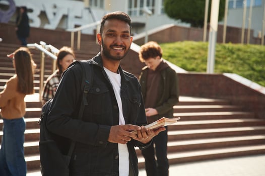 Indian man is standing in front of his friends. Four young students in casual clothes are together outdoors photo