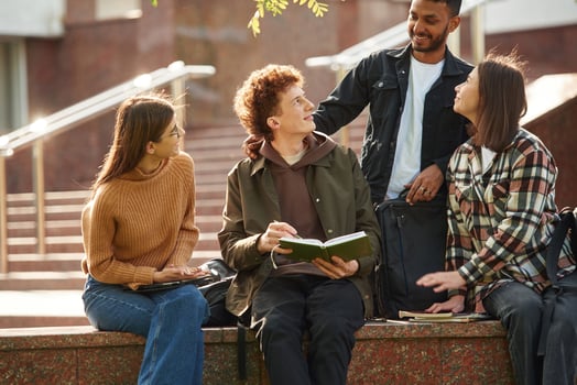 Hanging out after lessons. Four, young s,tudents in casual clothes are together outdoors photo