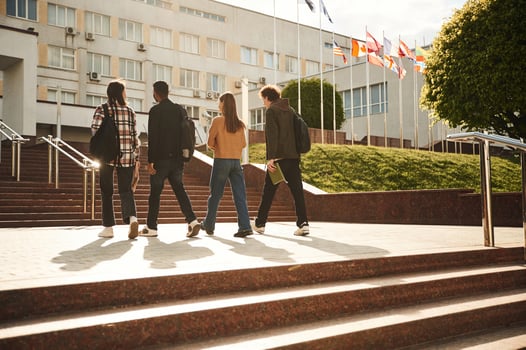 Going t,o the, university on the stairs. Four young students in casual clothes are together outdoors photo