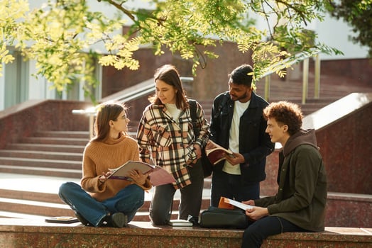Tree with ,green, leaves. Four young students in casual clothes are together outdoors photo