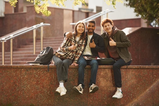 Three young students in casual clothes are together outdoors photo
