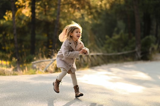 In the golden rays of the sun, a young girl dances down the road, her laughter and the light in her hair creating a magical moment. photo