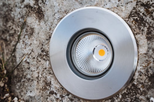 This image features a detailed closeup shot of a shining light fixture resting on a textured concrete surface, highlighting the reflections and interplay of light against the material photo