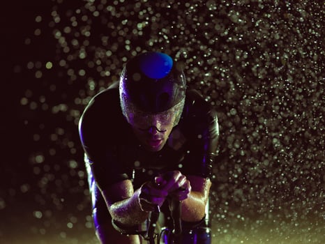 A triathlete braving the rain as he cycles through the night, preparing himself for the upcoming marathon photo