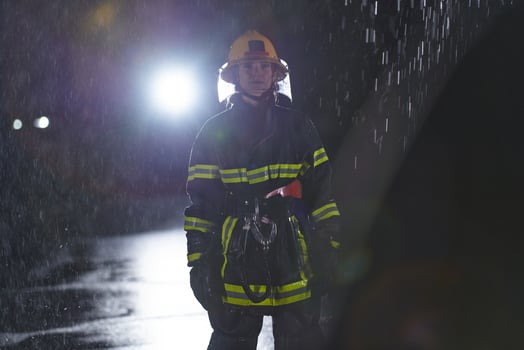 A determined female firefighter in a professional uniform striding through the dangerous, rainy night on a daring rescue mission, showcasing her unwavering bravery and commitment to saving lives. photo