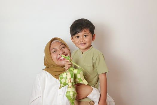 happy asian muslim mother and son making ketupat together at home before eid mubarak photo