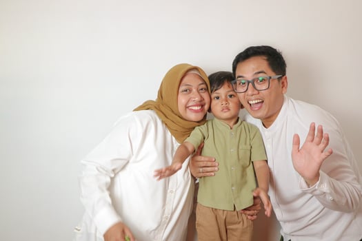 Portrait of Asian Muslim parents and son smile and embrace on isolated white background photo
