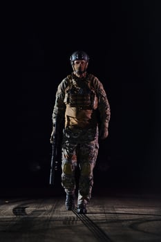 A professional soldier in full military gear striding through the dark night as he embarks on a perilous military mission photo