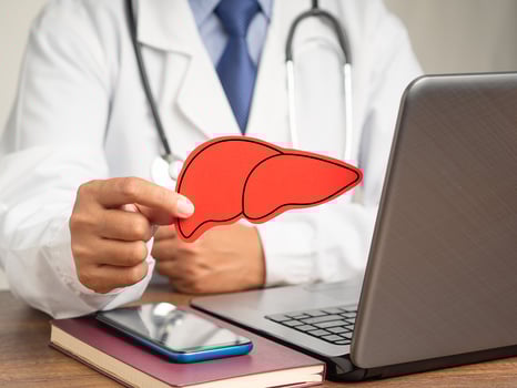 A doctor's holding a liver shape symbol while sitting in the hospital. photo