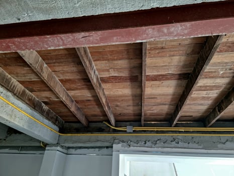 A ceiling with exposed wood beams and pipes photo