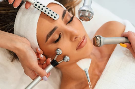 Hands, are, holding bunch of cosmetitian tools. Woman face getting facial care by beautician hands at spa salon photo