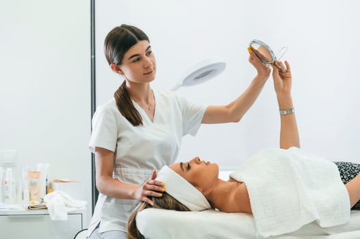 Taking a look in the mirror. Woman face getting facial care by beautician hands at spa salon photo
