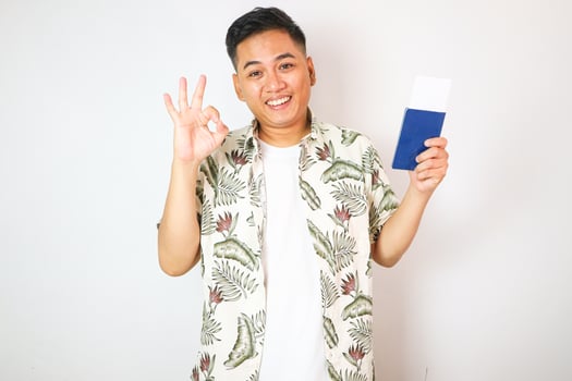 A happy asian guy shows his newly acquired Indonesian Passpor with ok sign, Isolated on a white background. photo
