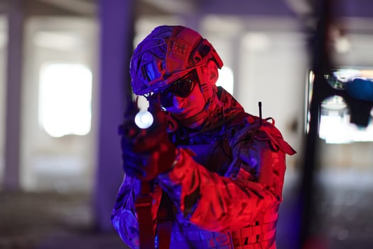 A professional soldier undertakes a perilous mission in an abandoned building illuminated by neon blue and purple lights photo