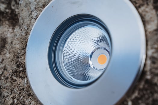 This image captures a detailed closeup view of a bright light installed above, illuminating a rough concrete surface below it, showcasing the contrast between materials photo
