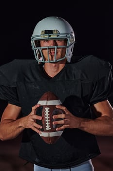 American Football Field. Lonely Athlete Warrior Standing on a Field Holds his Helmet and Ready to Play. Player Preparing to Run, Attack and Score Touchdown. photo