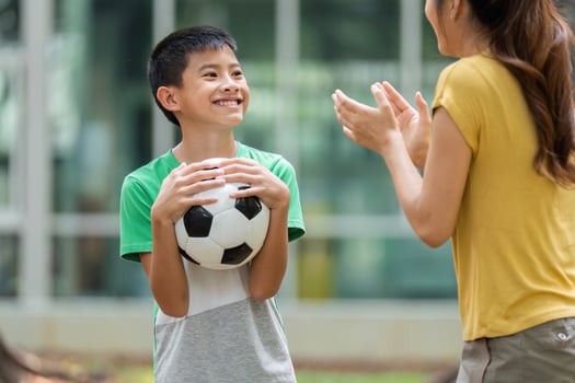 Encouragement and Growth in Sports. A young boy smiles at his mother, excited to play soccer, as she shows support. photo