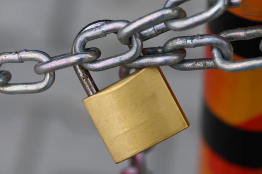 Golden padlock secured to a heavy metal chain on a vibrant construction site at midday photo