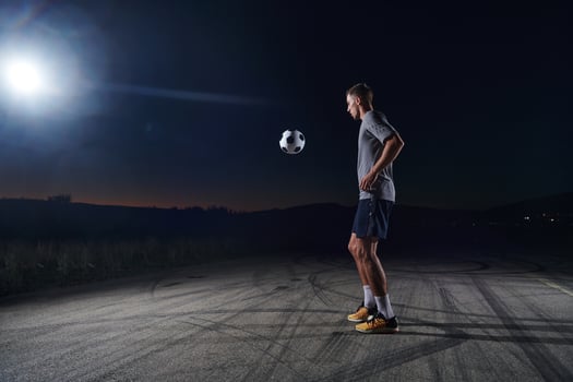 Portrait of a young handsome soccer player man on a street playing with a football ball photo