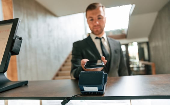 Making ,payment, by using phone and terminal. A man in a black jacket at the hotel reception photo