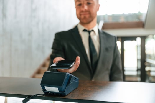 Making payment by using phone, and terminal. A man in a black jacket at the hotel reception photo