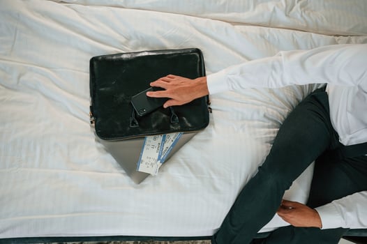 Close up view of businessman that is ,sitting on bed with tickets for travel on it photo