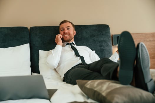 Having ,fun ,by talking by phone and lying down on bed. Businessman is indoors in the hotel room photo
