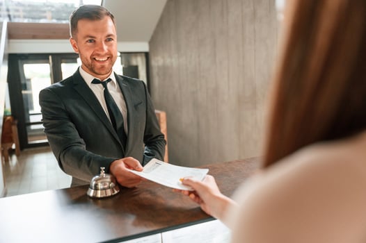 Woman serves, a visitor. A man in a black jacket at the hotel reception photo