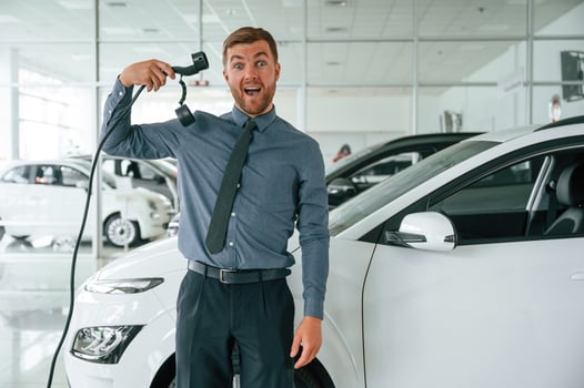 Having ,fun with ,,charger. Handsome car dealership worker is with electric vehicle photo