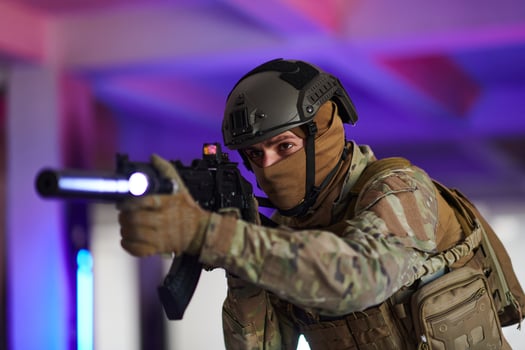 A professional soldier undertakes a perilous mission in an abandoned building illuminated by neon blue and purple lights photo