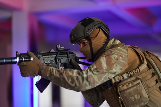 A professional soldier undertakes a perilous mission in an abandoned building illuminated by neon blue and purple lights photo