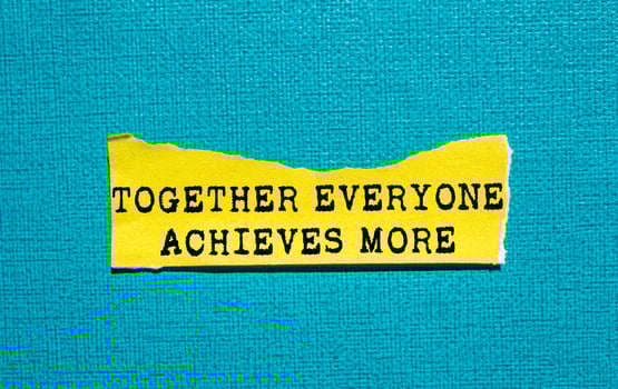 Together everyone achieves more message written on ripped torn yellow paper piece on blue background. Conceptual together everyone achieves more symbol. Copy space. photo