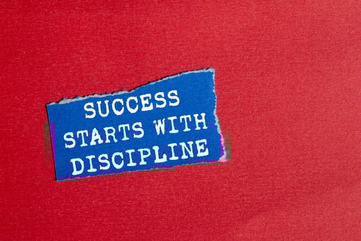Success starts with discipline message written on ripped torn blue paper piece on red background. Conceptual success starts with discipline symbol. Copy space. photo