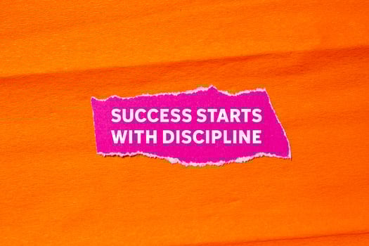 Success starts with discipline message written on ripped torn pink paper on orange background. Conceptual success starts with discipline symbol. Copy space. photo