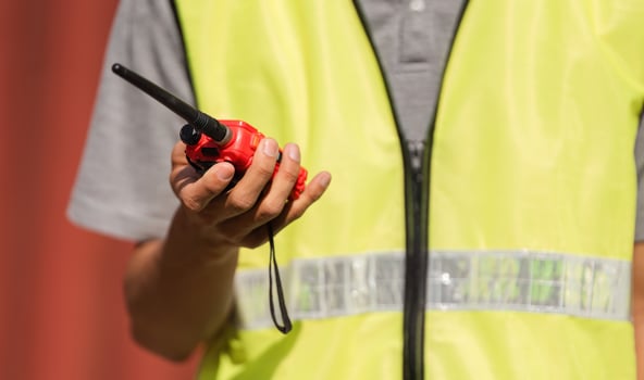 Construction manager holding a red walkie-talkie for communication in a safety vest photo