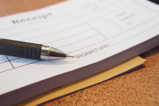 Receipt and pen lying on a wooden table during a transaction photo