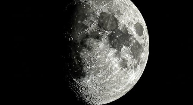 A close-up of the moon's surface showcasing detailed craters and dark areas in a dark night. photo