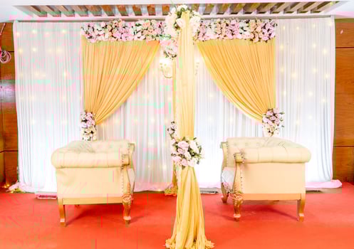 Bangladeshi wedding stage decoration with multi color flowers, props, and lights. Wedding stage decoration with white and yellow theme. Bride and groom seating stage photo