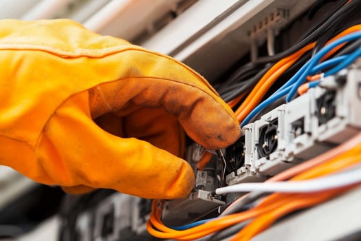 A person wearing gloves is holding an electrical wire photo