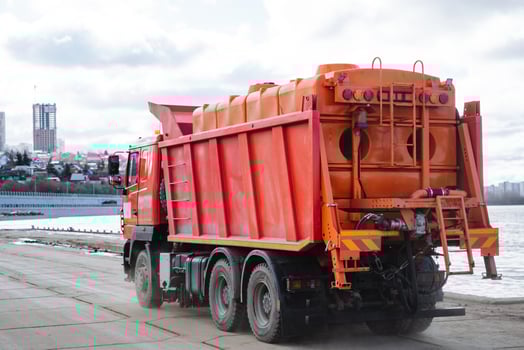A red dump truck, painted in a bright shade of crimson, is currently parked conveniently on the side of the road, ready for its next task, whether it be for construction or transport needs photo