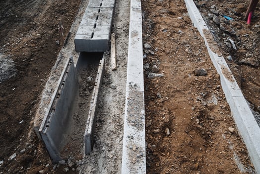 A concrete drain is currently being constructed along the side of a busy road to effectively manage water flow and drainage, ensuring proper infrastructure maintenance and efficiency photo