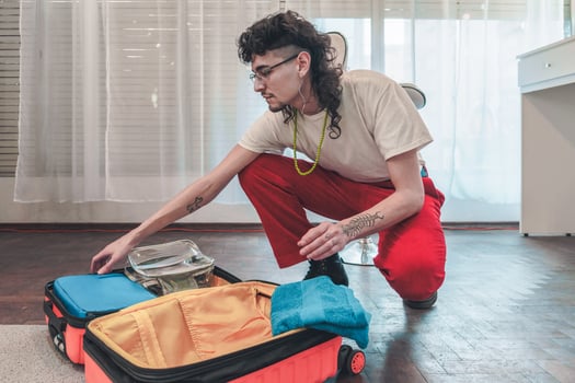 Young man packing clothes and accessories in suitcase for travel photo
