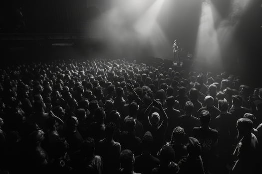A vibrant crowd of enthusiastic fans stands closely packed in a dark concert space, eagerly anticipating the performance ahead photo
