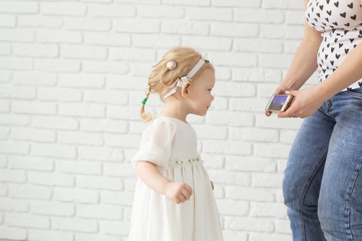 Child with cochlear implant hearing aid having fun with mother in room background with copy space and place for advertising - diversity and deafness treatment and medical innovative technologies photo