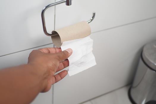 Hand reaching for toilet paper in a modern bathroom setting photo