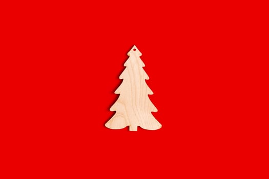 Flat natural unpainted wooden spruce shape on red background. photo